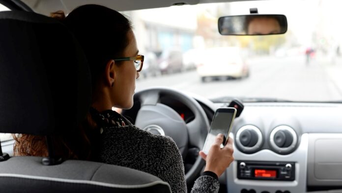 Woman in car looking at smartphone