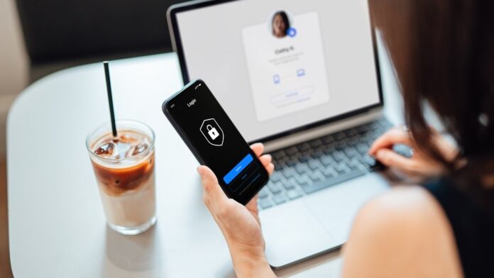 Young Business Woman Logging in Online Security System On Laptop With Mobile App On Smartphone