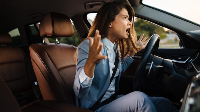 Upset businesswoman yelling while driving a car
