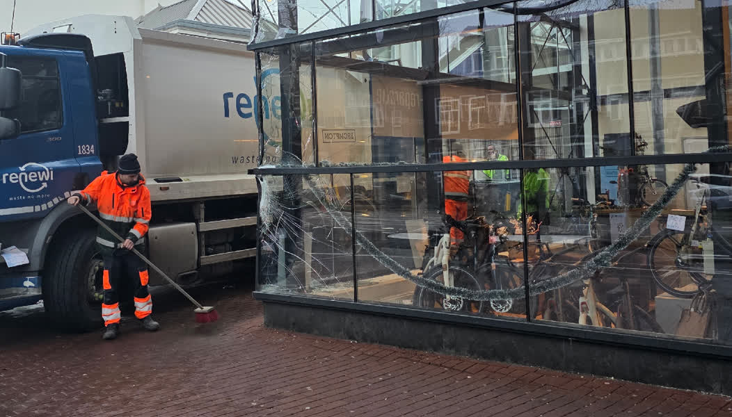 Afvalwagen beukt tegen fietsenwinkel station